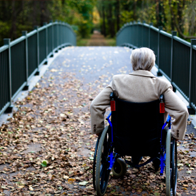 Senior with wheelchair in front of a bridge