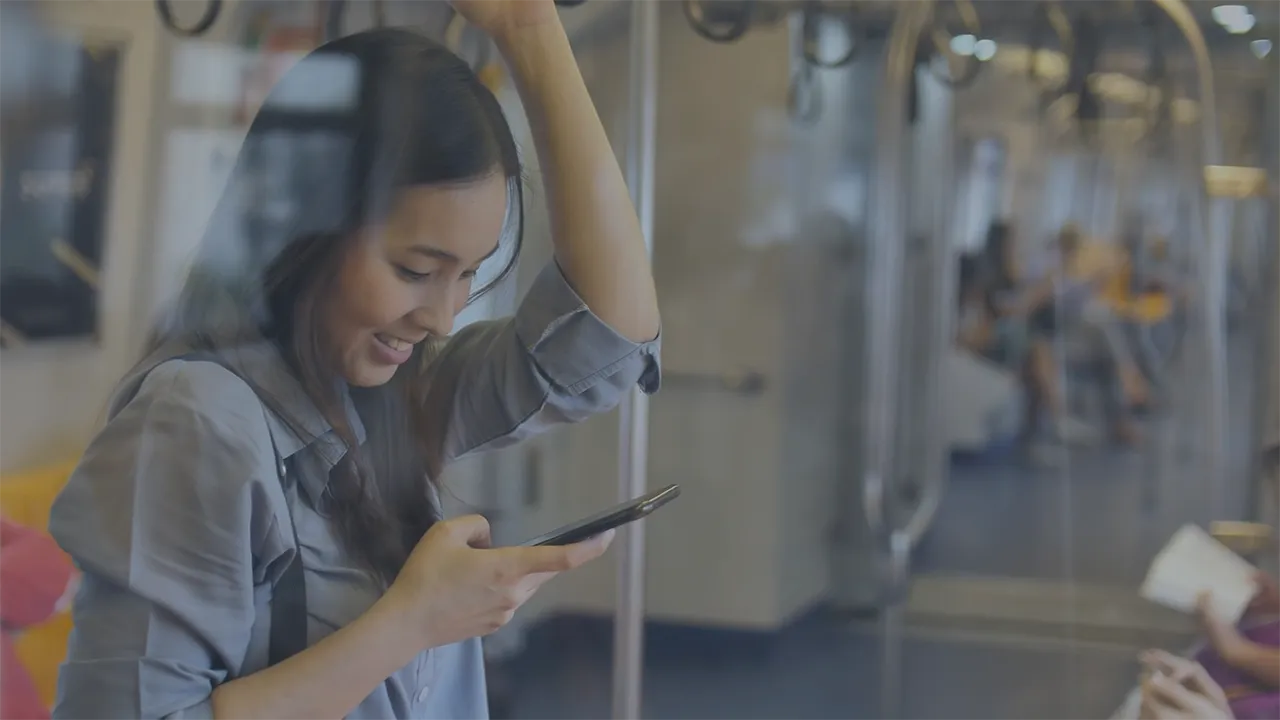 A young woman on her cell phone while riding a subway train