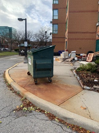 Garbage dumpster blocking sidewalk near student residence